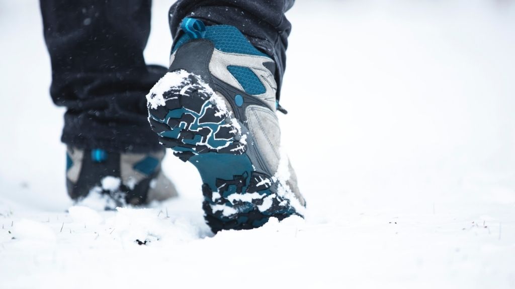 Bilden föreställer en närbild av ett par vinterskor som används i snö. Skorna är turkosa och gråa.