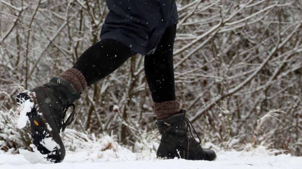 Vinterlandskap med ett par ben som går förbi med kängor och täckkjol